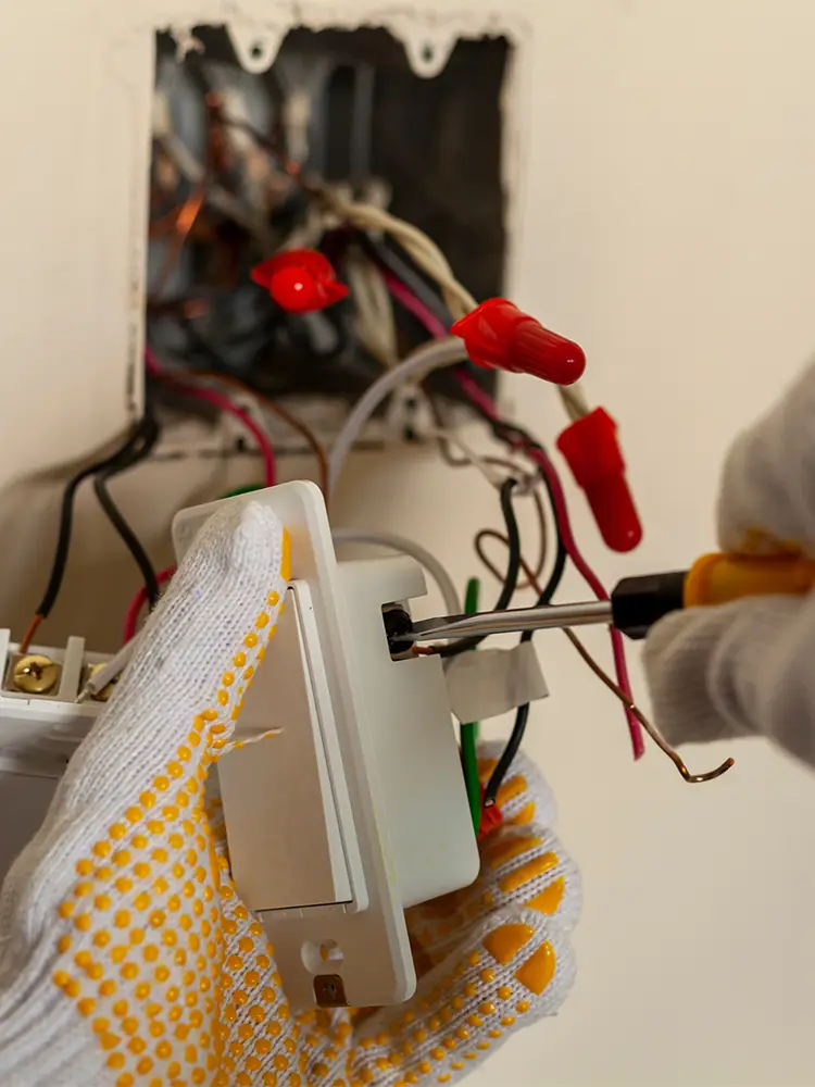 Ein Elektriker tauscht einen Wandschalter aus.